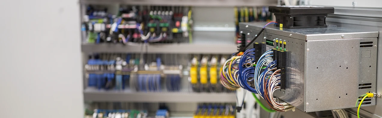 Cette image montre un PC industriel câblé, monté dans un boîtier métallique à l'intérieur d'un armoire de commande, illustrant l'expertise de fabrication de Cloos Electronic dans la construction d'appareils. Le PC, les cartes électroniques et les faisceaux de câbles sont tous fabriqués chez Cloos Electronic.