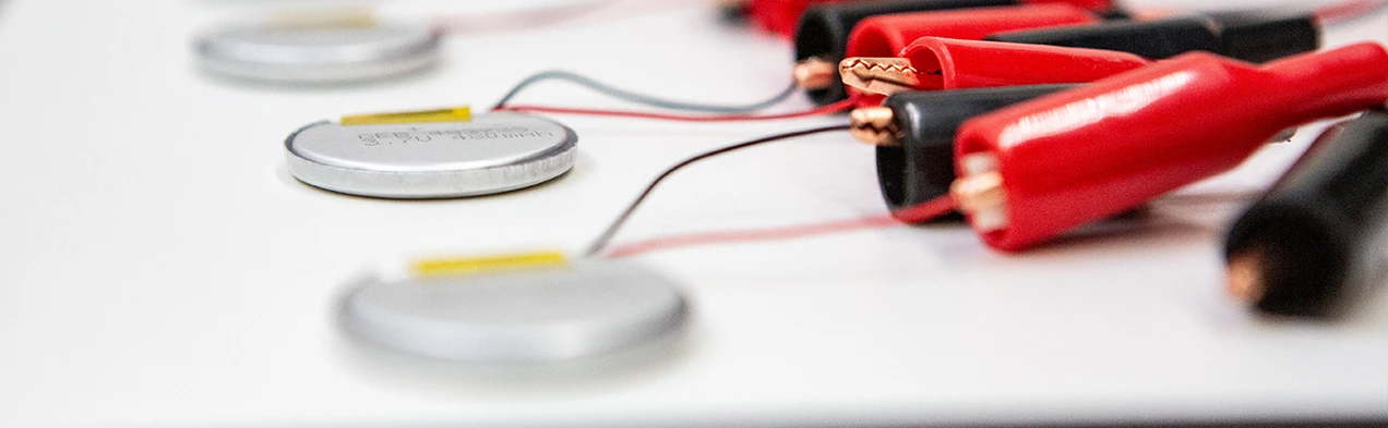 Cette image montre de petites batteries LiPo rondes connectées à un testeur de batterie, démontrant l'expertise de Cloos Electronic dans l'approvisionnement de batteries. Elle souligne la capacité à tester et fournir des batteries de haute qualité pour diverses applications.