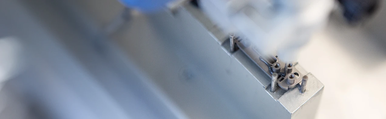 Cette image montre un distributeur automatique de colle appliquant de l'adhésif sur un mécanisme de précision, illustrant la technologie d'automatisation avancée dans l'assemblage mécanique chez Cloos Electronic. Ce processus améliore la précision et l'efficacité dans la fabrication.